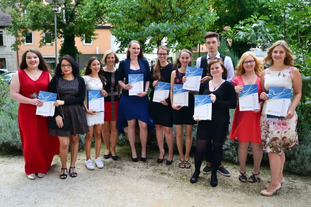 Abgebildet sind Schülerinnen und Schüler mit ihren Europapässen Mobilität 2017, aufgenommen in einem Park nach der Jahresabschlussfeier 2016/2017 in Erlangen.