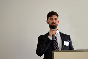 Zu sehen ist der IFA-Absolvent Alexander Podarewski während seines Vortrags beim Career Day 2017 des IFA mit einem Mikrofon in der Hand.