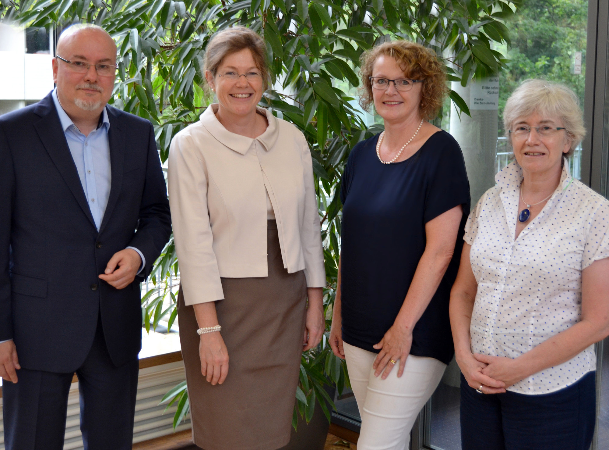 Herr Prof. Dr. Daniel Gossel, Schulleiter, Frau Susanne Bleise, stellvertretende Schulleiterin und Herr Stephan Paul, stellvertretender Schulleiter und Geschäftsführer stehen vor der verglasten Bibliothek