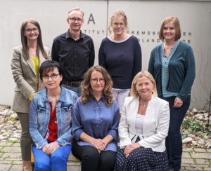 7 Personen vor einer Steinwand